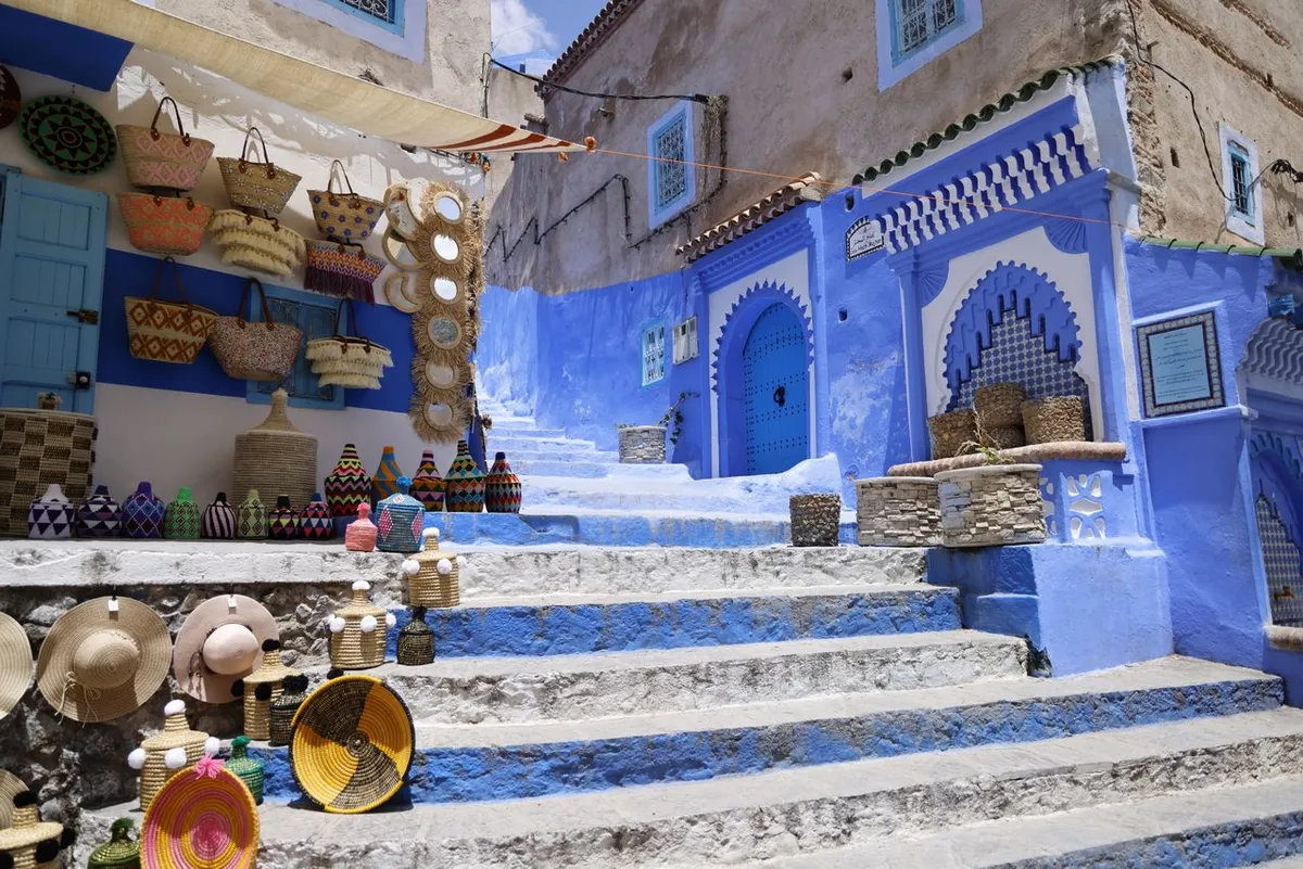 Baskets, straw hats and woven pots displayed on the steps of a blue lane