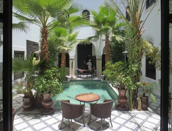 The courtyard of a riad with its pool and palm trees