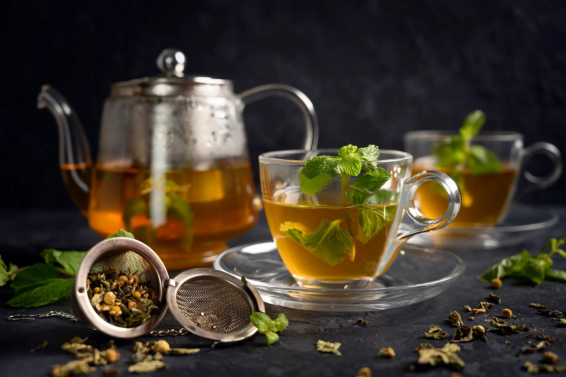 A teapot and glasses of mint tea on a dark table