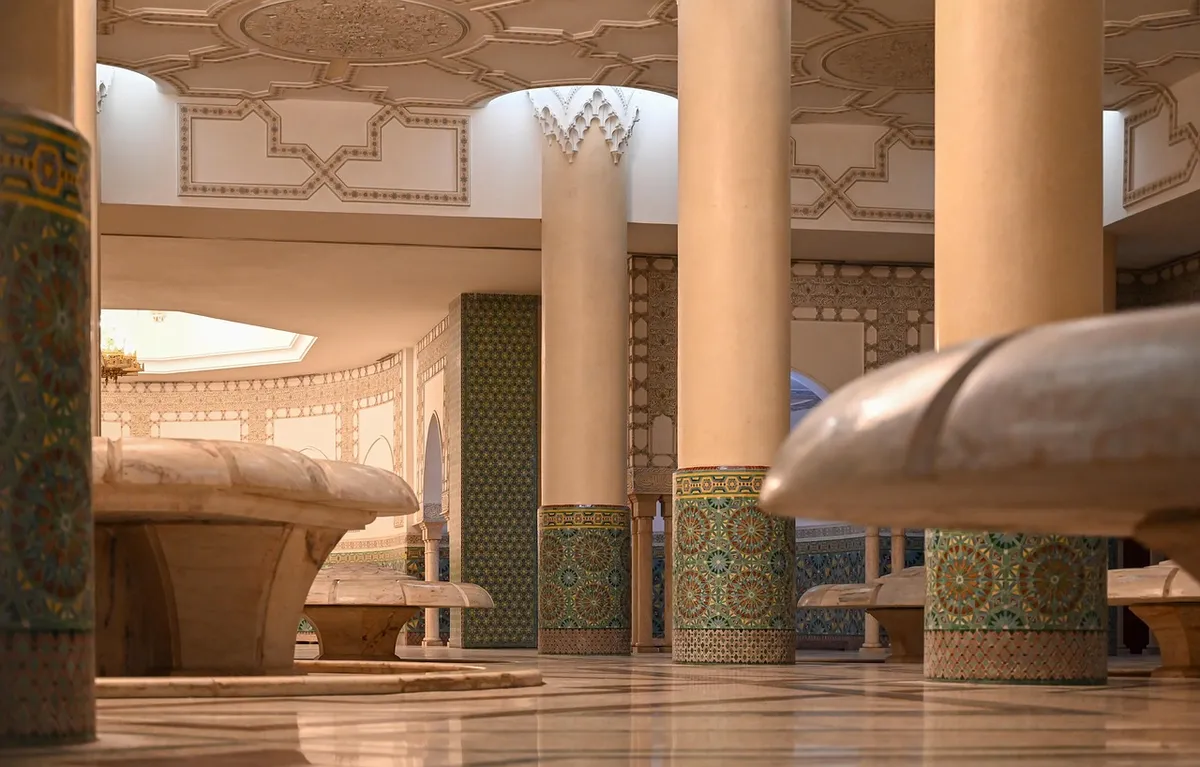 Columns covered in zellige and marble fountains shaped like open flowers in the ablution hall of the Hassan II Mosque