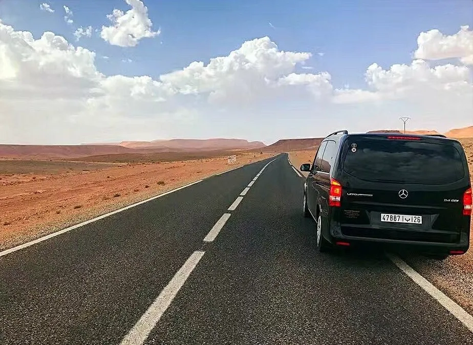 A black van stopped by a road in the south, between red plateaus