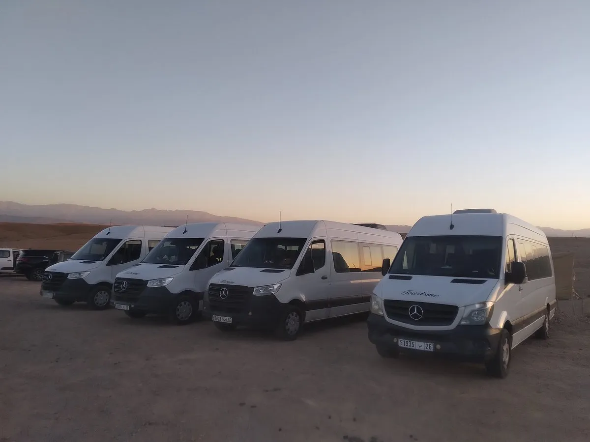 Four white minibuses lined up at dusk, with the Atlas on the horizon