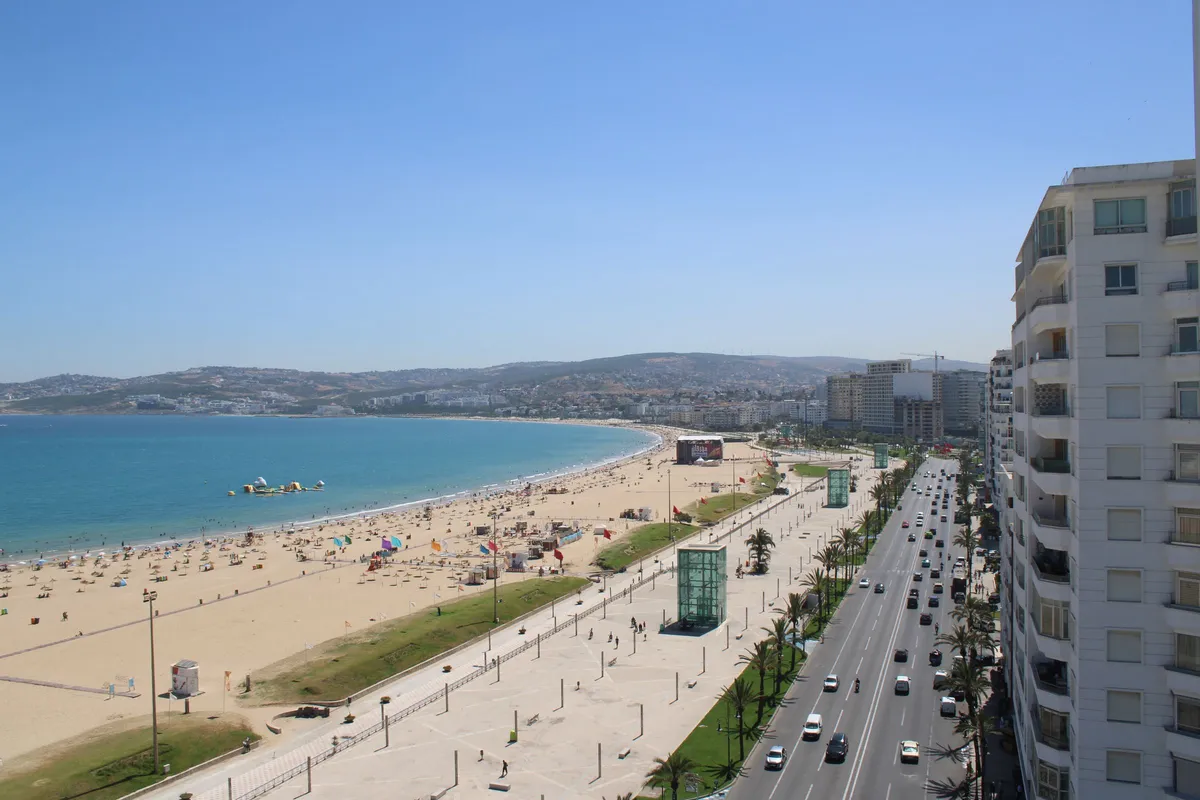 La grande plage de sable de la baie de Tanger le long de la corniche, de ses palmiers et de ses immeubles